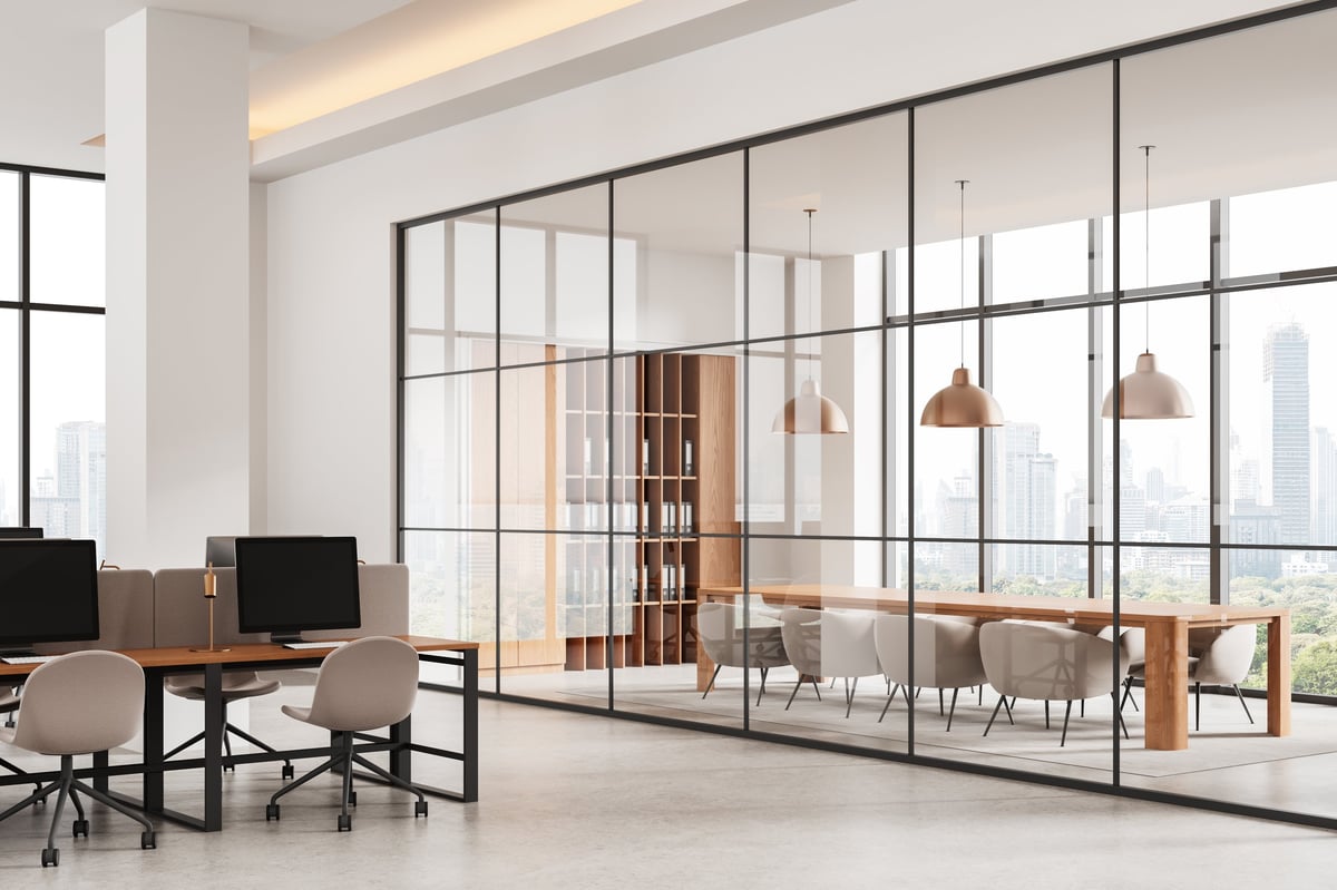 Oficina contemporánea con mesas compartidas y sala de reuniones acristalada
